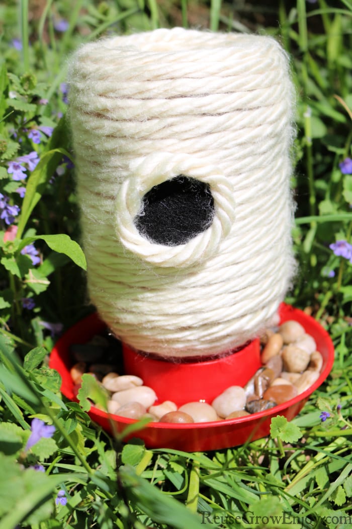 Finished bee feeder sitting in grass and purple flowers