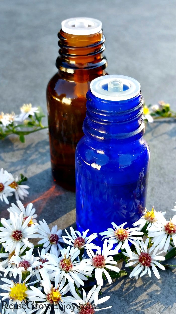 One brown and one blue small essential oil bottle with little white flowers all around them.
