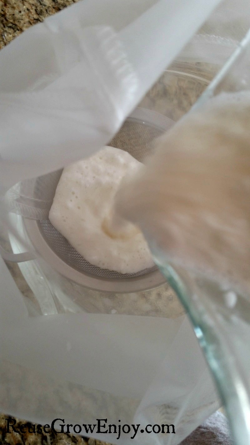Blended coconut water mixture being poured from blender into a nut bag