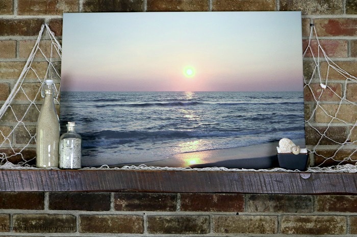Sunrise over ocean canvas print on shelf with beach items around.