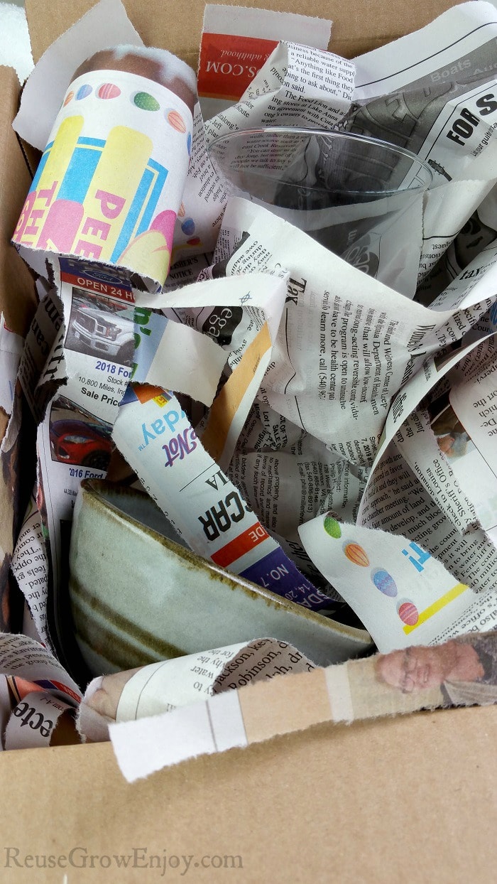 Glass items packed in newspaper inside of cardboard box.