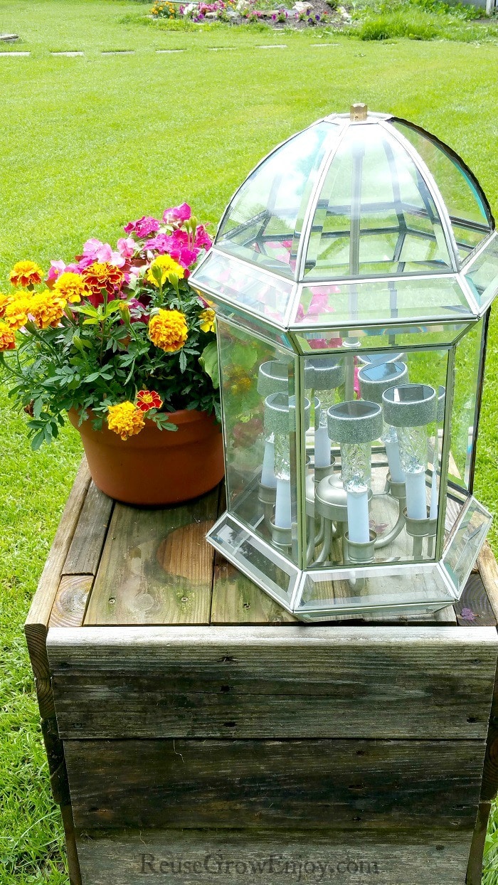 Solar light on wood table with flowers next to it.