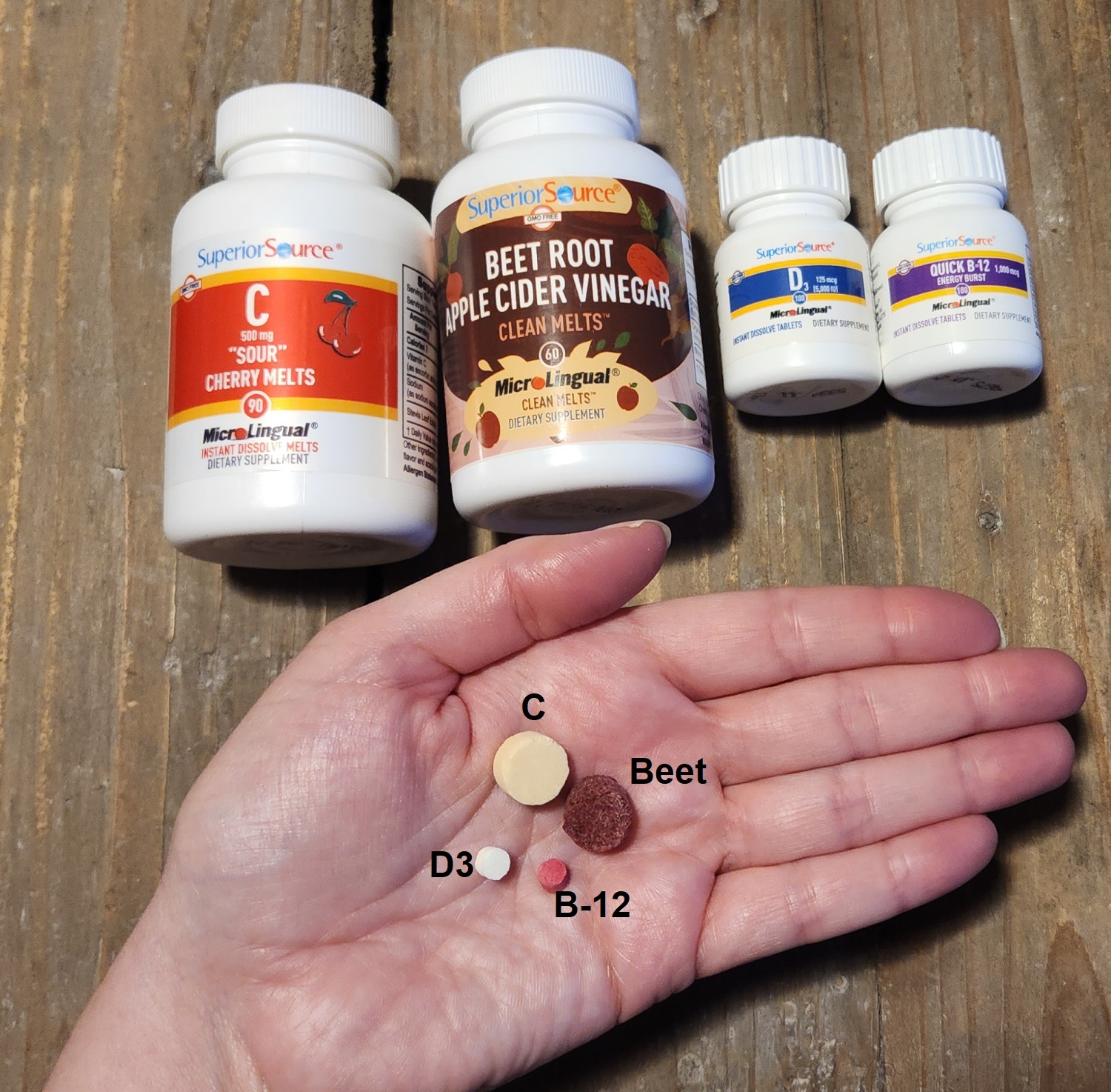 SSV bottles in back flat hand holding pills in hand all with wood background