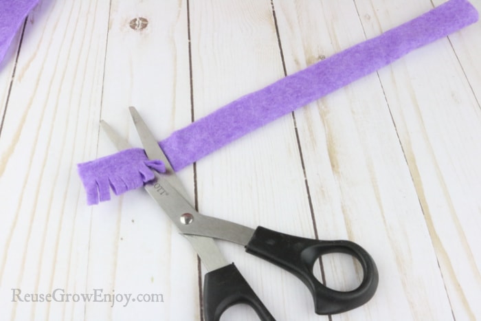 Scissors cutting small cuts in felt strip