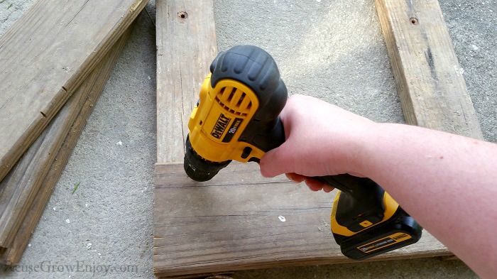 Hand with DeWalt drill attaching boards to 2x4's.