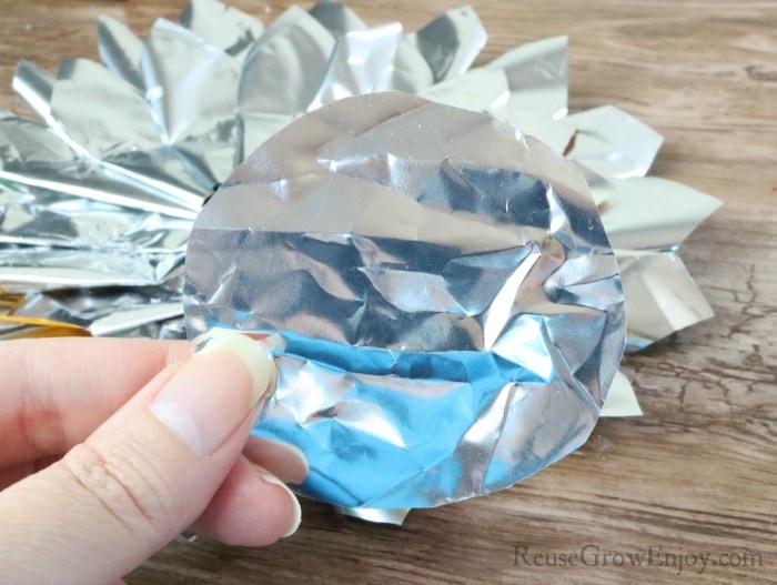 Hand holding piece of chip bag cut into a circle