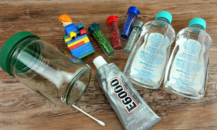 Supplies to make a LEGO snow globe, e600, qtip, glitter, mineral oil, legos and a jar.