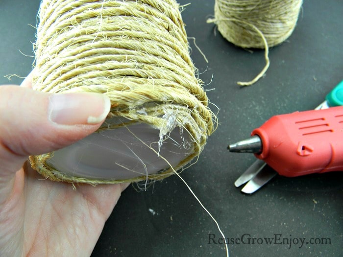 Cut the twine spool from the bottle and use hot glue to attach to bottom of bottle