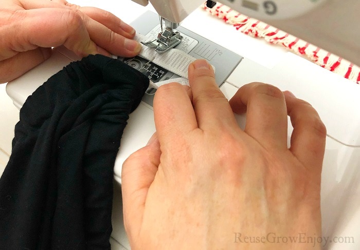 Hands holding the elastic together as it is stitched together on the sewing machine.