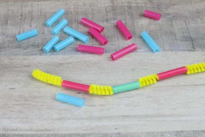 Cut pieces of straw with a yellow pipe cleaner running through them.