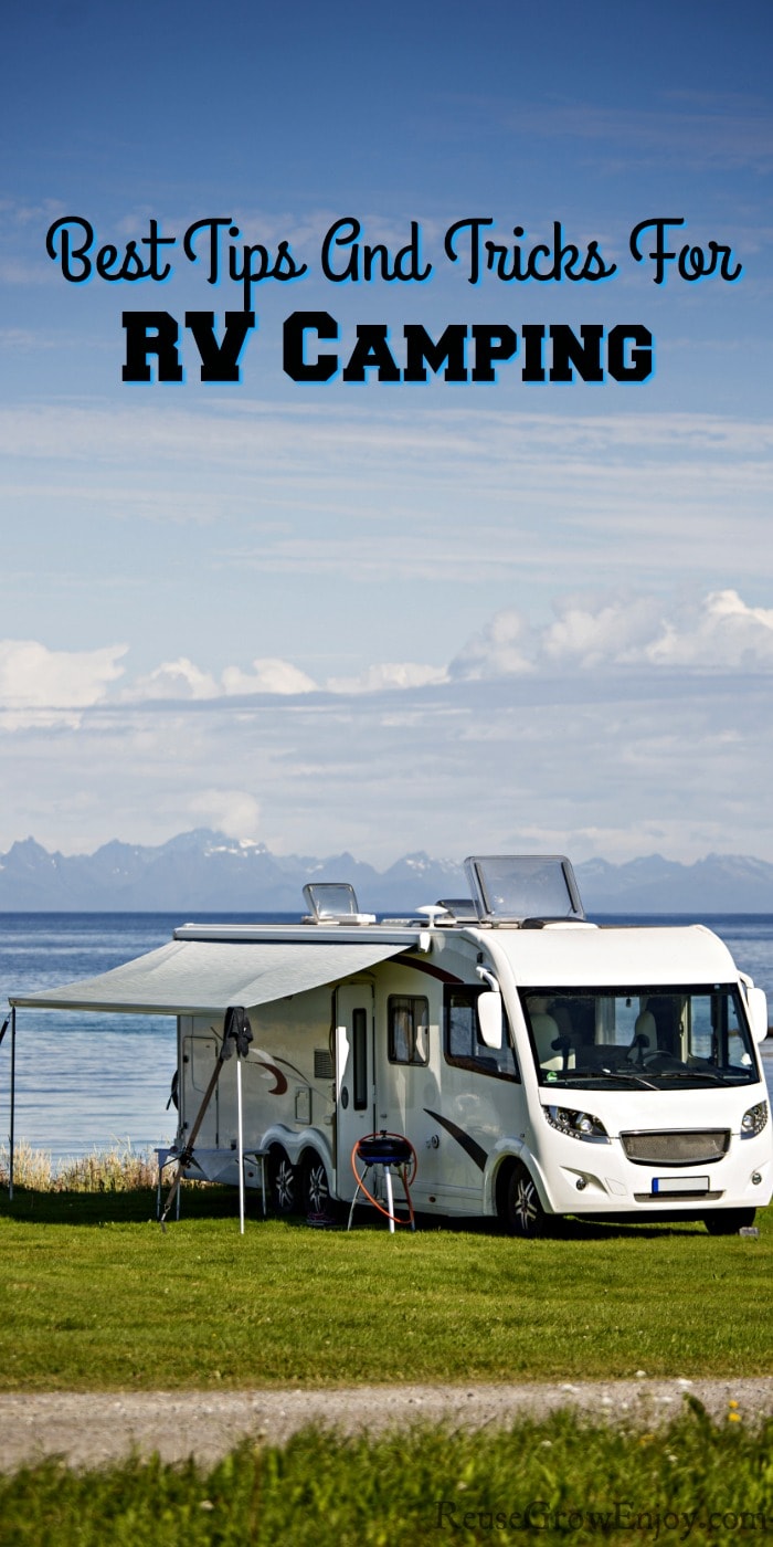 RV camping by water with green grass around it. Text overlay on the top that says Best Tips And Tricks For RV Camping