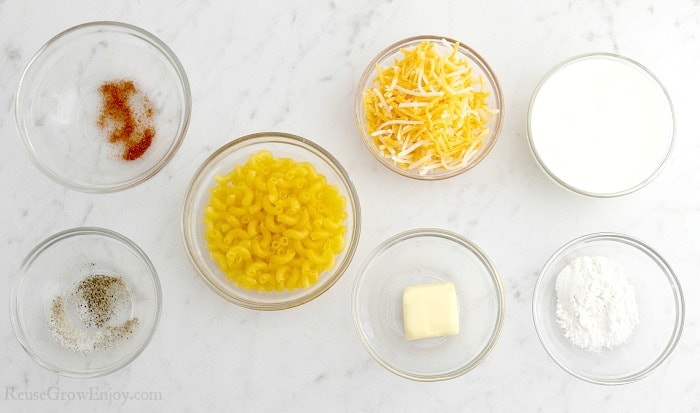Small clear glass bowls full of all the things needed to make macaroni and cheese.