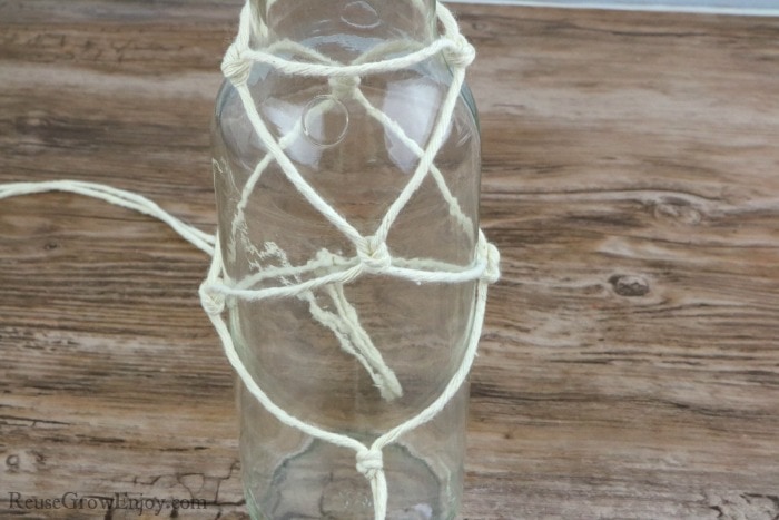 Tie knots in string to make netting on bottle