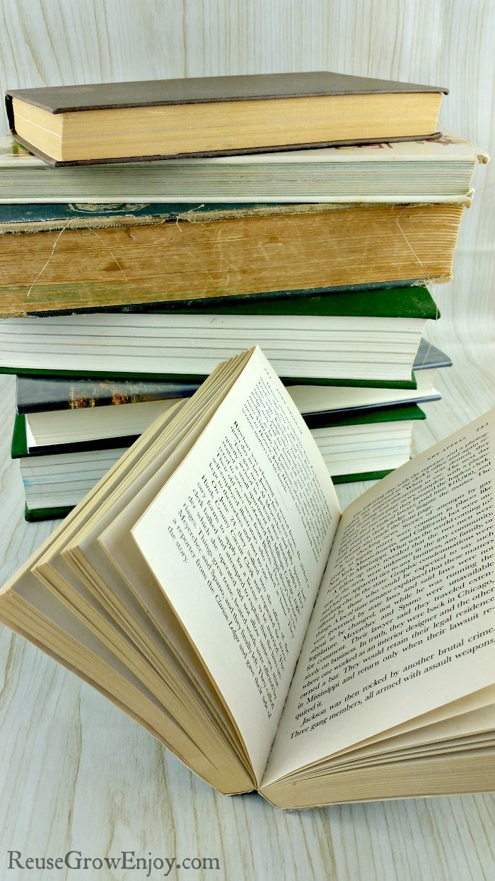 Stack of old books in background and open book in front