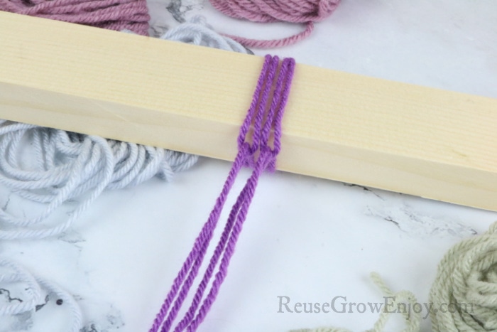 Purple yarn looped onto wood