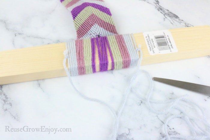 Adding a piece of yarn at the top of wood to make a hanger