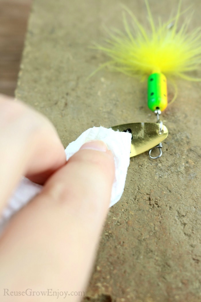 Hand with paper towel wiping off marker from lure