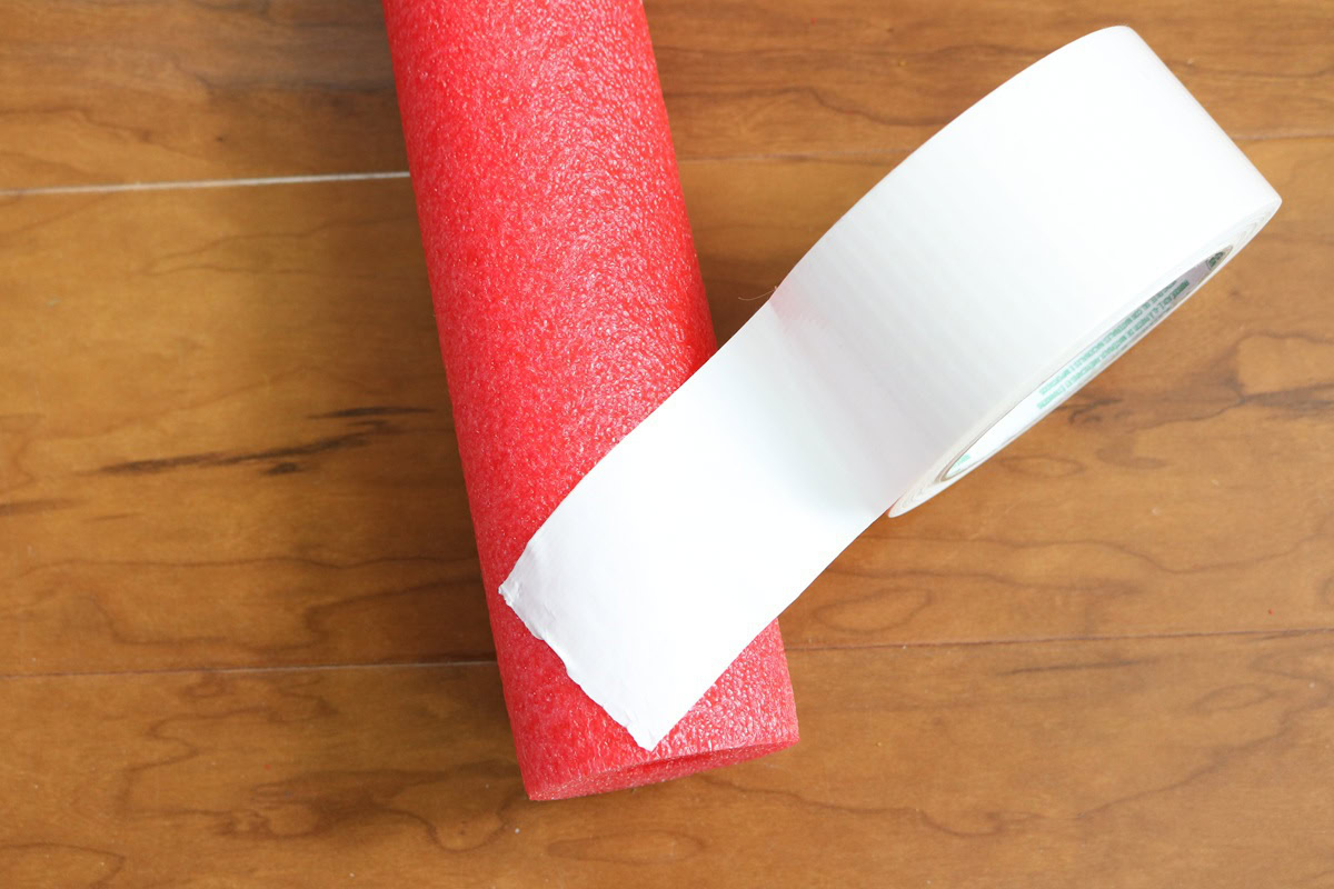 Red pool noodle and white tape for DIY giant candy cane craft.