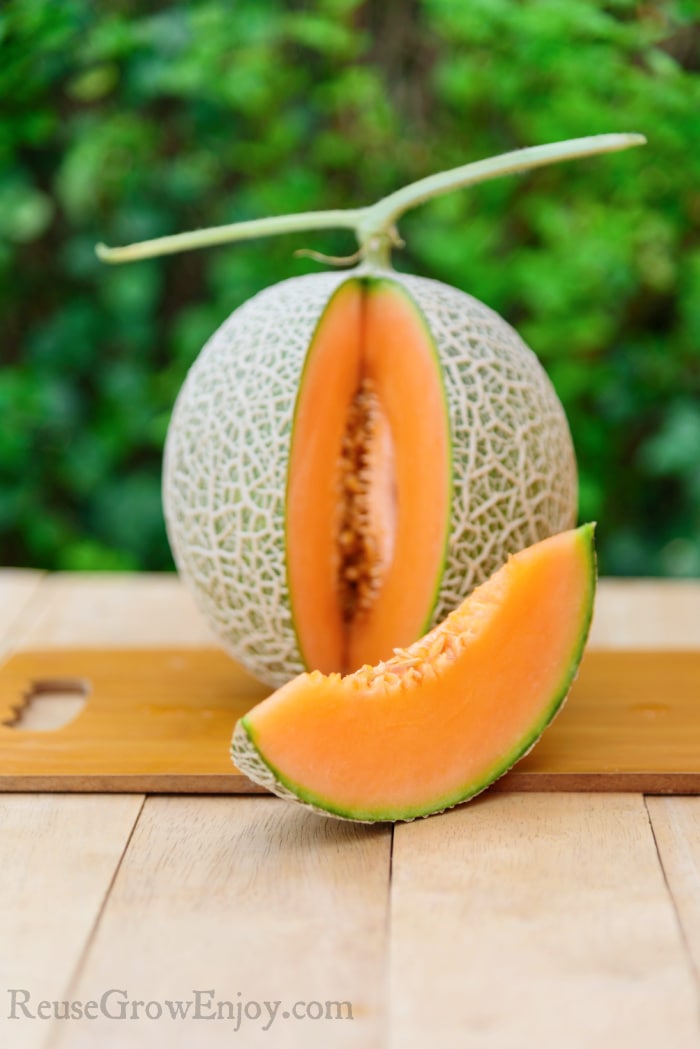 cantaloupe on cutting board with one slice cut out
