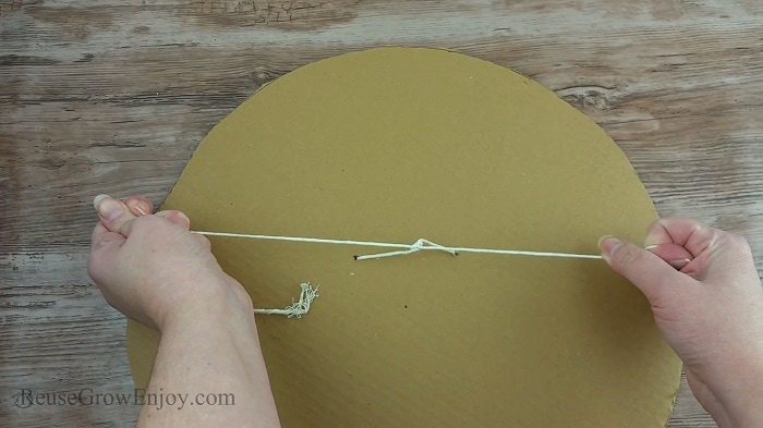 String in the center of the round cardboard being tied into a knot.